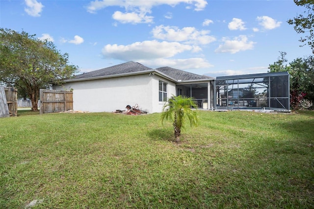 rear view of house with a lawn and glass enclosure