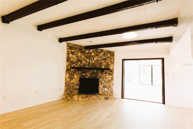 unfurnished living room featuring beam ceiling, a textured ceiling, a fireplace, and hardwood / wood-style floors