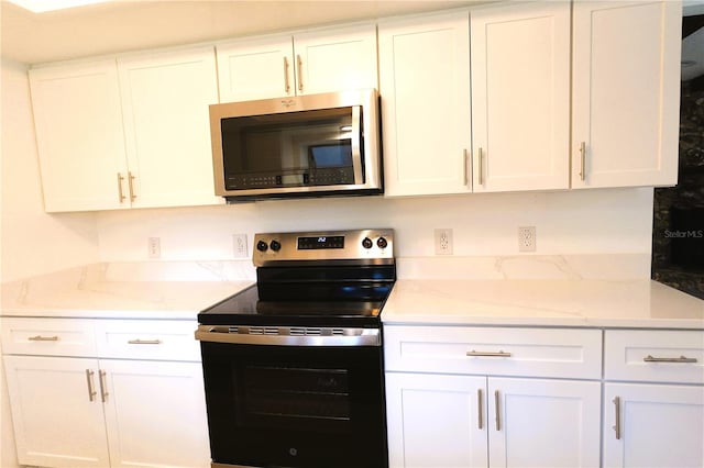 kitchen with light stone countertops, white cabinets, and stainless steel appliances