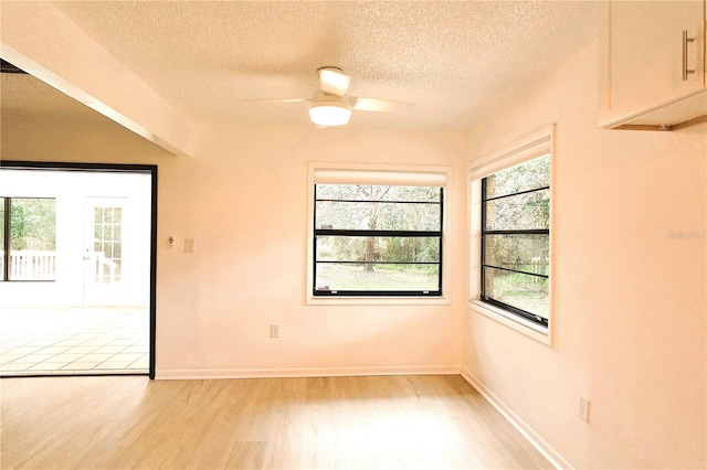 empty room featuring a textured ceiling, light hardwood / wood-style floors, and ceiling fan