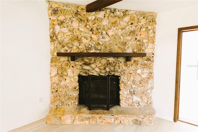 interior details with a stone fireplace, a textured ceiling, and beam ceiling