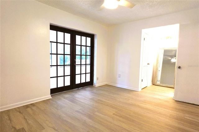 spare room featuring light hardwood / wood-style floors, french doors, a textured ceiling, and ceiling fan