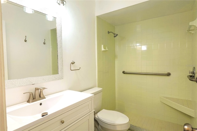 bathroom with vanity, tiled shower, and toilet