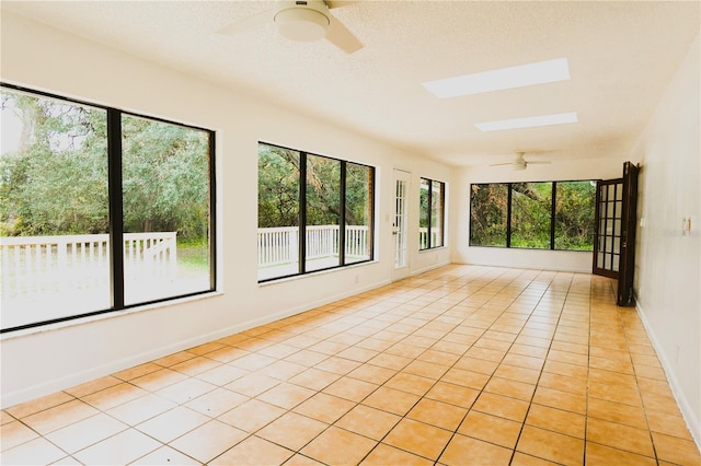 unfurnished sunroom with ceiling fan and a skylight