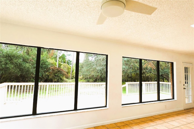 interior space with ceiling fan, a wealth of natural light, and light tile patterned floors