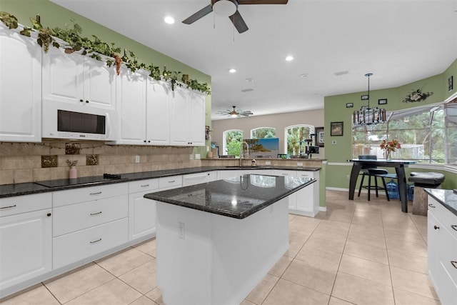 kitchen with decorative light fixtures, a center island, black electric stovetop, and plenty of natural light