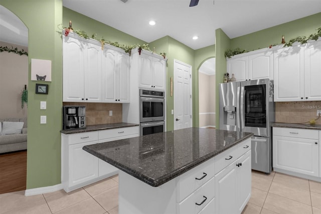 kitchen featuring stainless steel appliances, white cabinets, decorative backsplash, and a center island