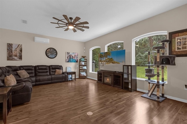 living room with dark wood-type flooring, ceiling fan, and an AC wall unit