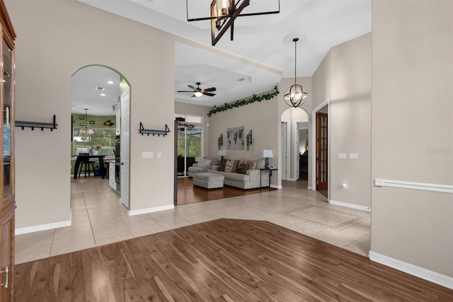 interior space with ceiling fan with notable chandelier and light wood-type flooring