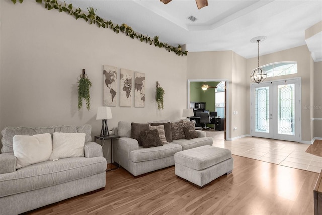 living room featuring hardwood / wood-style floors, ceiling fan with notable chandelier, and french doors