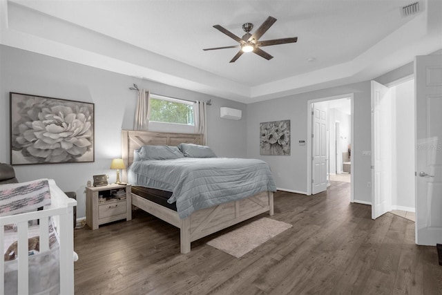 bedroom with a raised ceiling, a wall mounted air conditioner, ceiling fan, and dark hardwood / wood-style floors