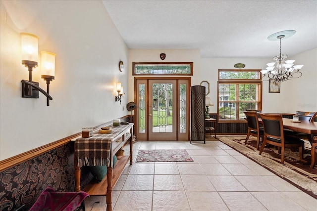 tiled entryway with a textured ceiling and a notable chandelier