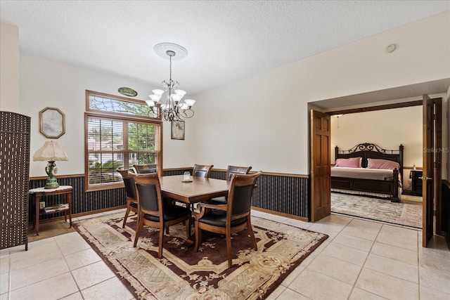 dining room featuring an inviting chandelier, light tile patterned floors, and a textured ceiling