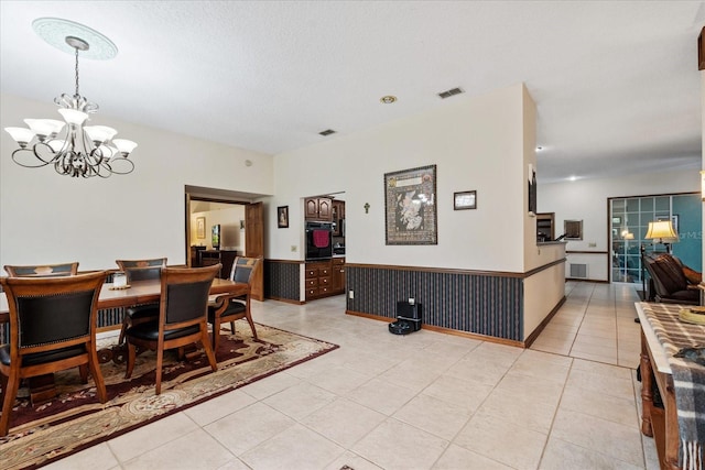 tiled dining room with a notable chandelier and a textured ceiling