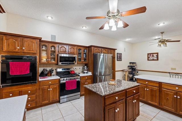 kitchen featuring light tile patterned floors, backsplash, a kitchen island, and appliances with stainless steel finishes