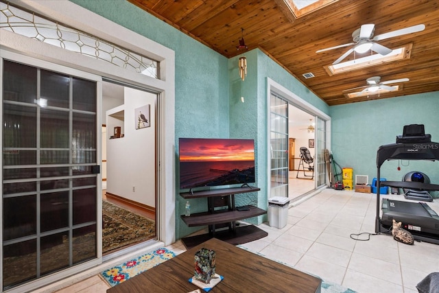 interior space with wood ceiling, a skylight, tile patterned floors, and ceiling fan