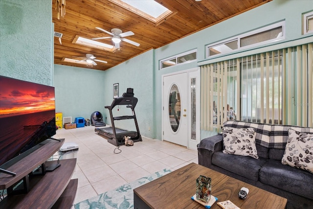 tiled living room featuring wood ceiling, vaulted ceiling with skylight, and ceiling fan