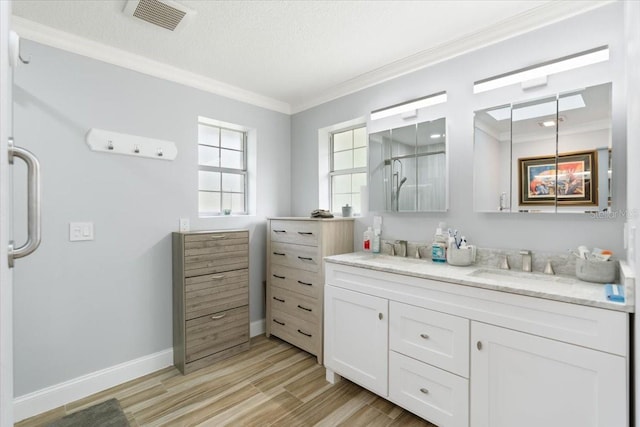 bathroom with wood-type flooring, a textured ceiling, ornamental molding, vanity, and a shower with shower door