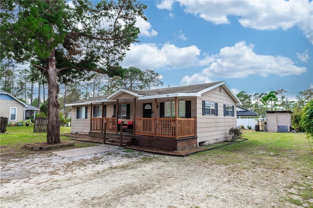 view of front of house with a front lawn, a shed, and covered porch