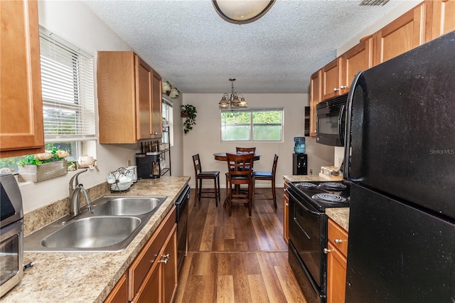 kitchen with plenty of natural light, black appliances, dark wood-type flooring, and sink