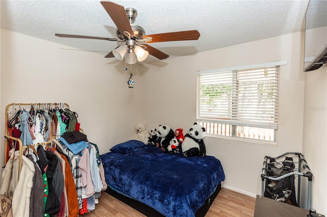 bedroom with light hardwood / wood-style floors, a textured ceiling, and ceiling fan