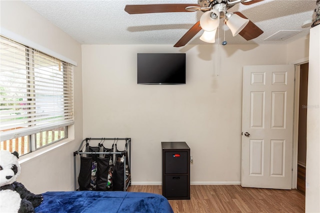 bedroom featuring light hardwood / wood-style floors, a textured ceiling, and ceiling fan