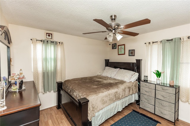 bedroom with ceiling fan, a textured ceiling, and light hardwood / wood-style floors