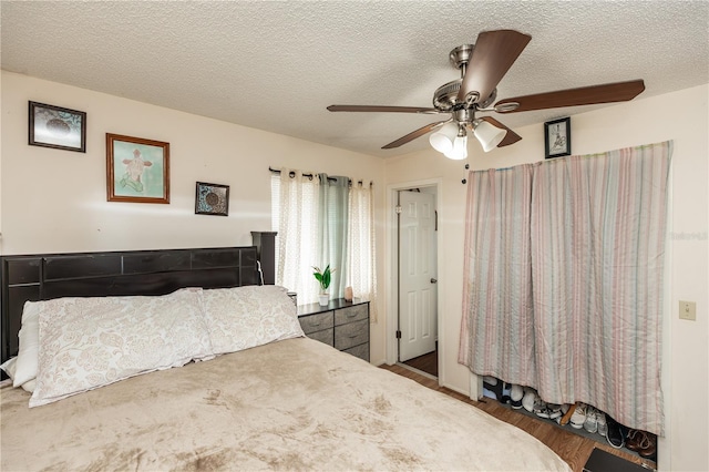 bedroom featuring dark hardwood / wood-style flooring, a textured ceiling, and ceiling fan