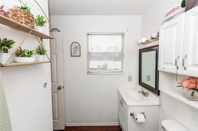 bathroom featuring toilet, hardwood / wood-style floors, vanity, and a textured ceiling