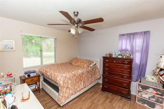 bedroom featuring a textured ceiling, light hardwood / wood-style flooring, and ceiling fan