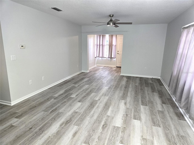 unfurnished room with a textured ceiling, ceiling fan, and light hardwood / wood-style flooring