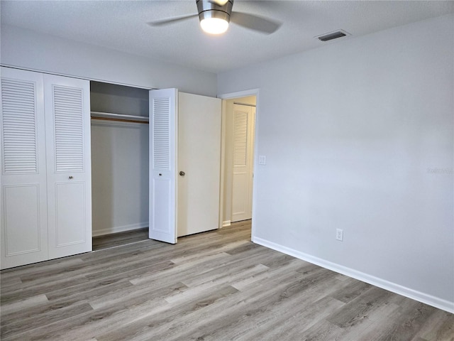 unfurnished bedroom featuring a textured ceiling, light wood-type flooring, ceiling fan, and a closet