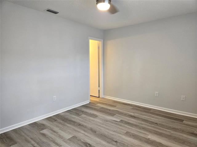 spare room featuring light wood-type flooring, a textured ceiling, and ceiling fan