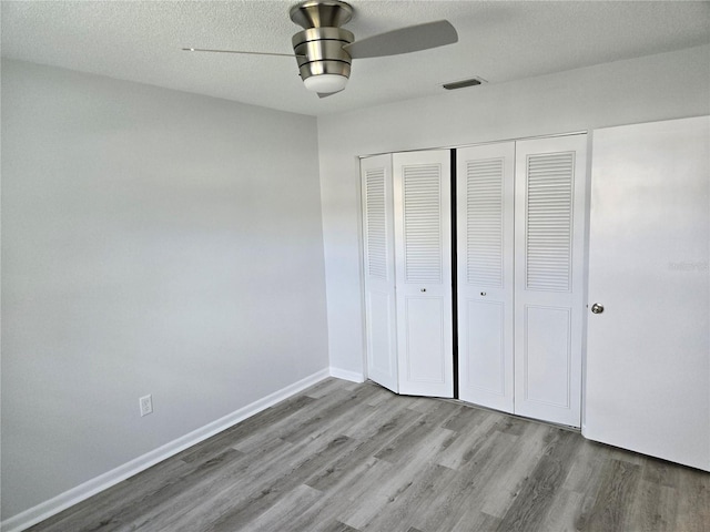 unfurnished bedroom featuring light hardwood / wood-style floors, ceiling fan, a textured ceiling, and a closet