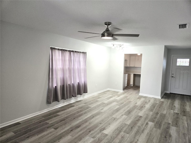 unfurnished living room featuring hardwood / wood-style floors, ceiling fan, and a textured ceiling