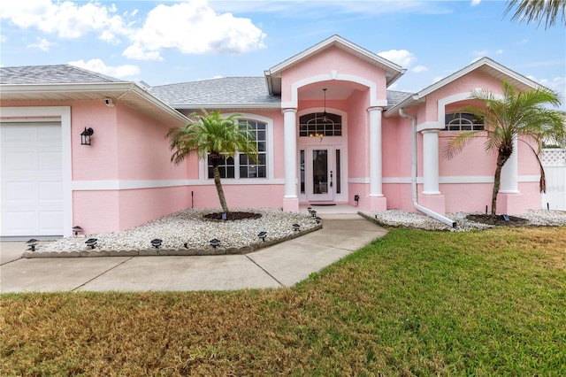 view of exterior entry with a garage, a yard, and french doors