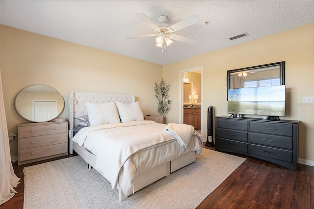 bedroom featuring ceiling fan, dark hardwood / wood-style flooring, a textured ceiling, and ensuite bath