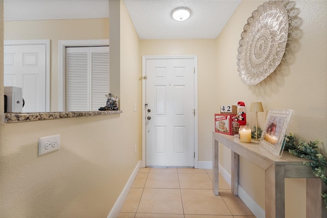 doorway to outside featuring light tile patterned floors and a textured ceiling