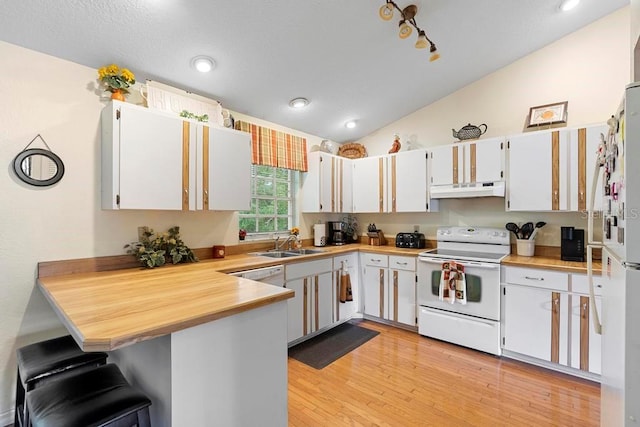 kitchen with lofted ceiling, white cabinets, kitchen peninsula, light hardwood / wood-style flooring, and white appliances