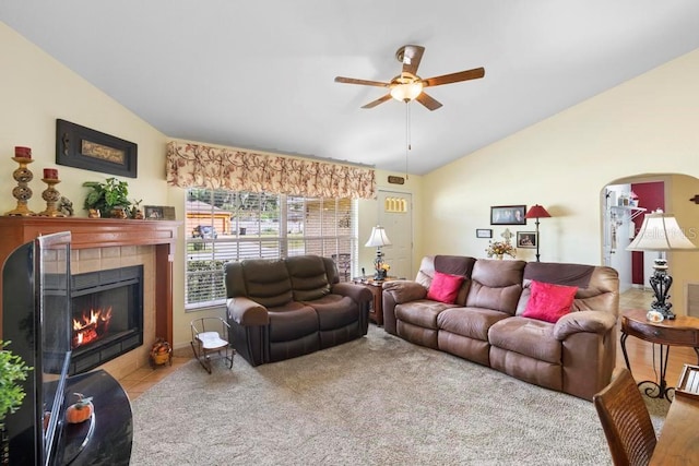 living room featuring ceiling fan, a tile fireplace, vaulted ceiling, and light tile patterned flooring