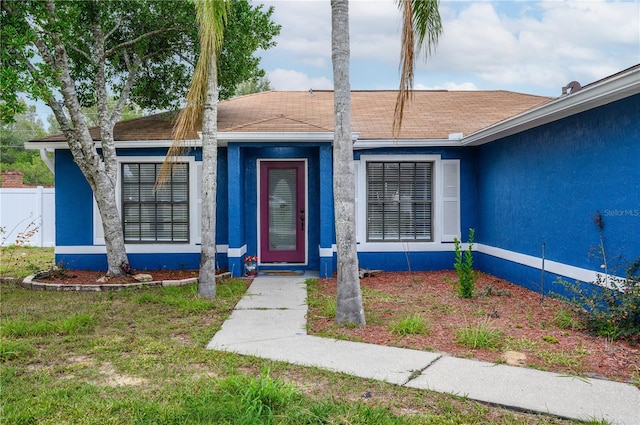 1171 Daimler Dr, Apopka, FL 32712 - doorway to property featuring stucco siding, fence, and roof with shingles
