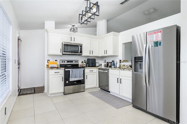 1171 Daimler Dr, Apopka, FL 32712 - kitchen with stainless steel appliances, white cabinets, hanging light fixtures, light tile patterned floors, and vaulted ceiling