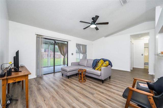 living room with a textured ceiling, light hardwood / wood-style floors, ceiling fan, and vaulted ceiling