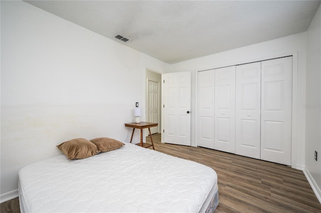 bedroom with a textured ceiling, dark hardwood / wood-style floors, and a closet