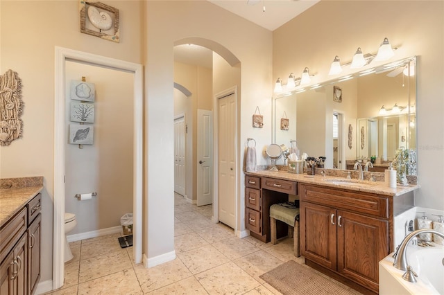 bathroom featuring tile patterned flooring, vanity, toilet, and a tub