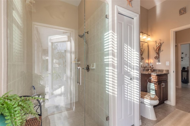 bathroom featuring toilet, vanity, tile patterned floors, and an enclosed shower