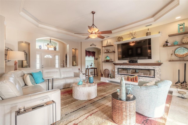 living room with a raised ceiling and ceiling fan