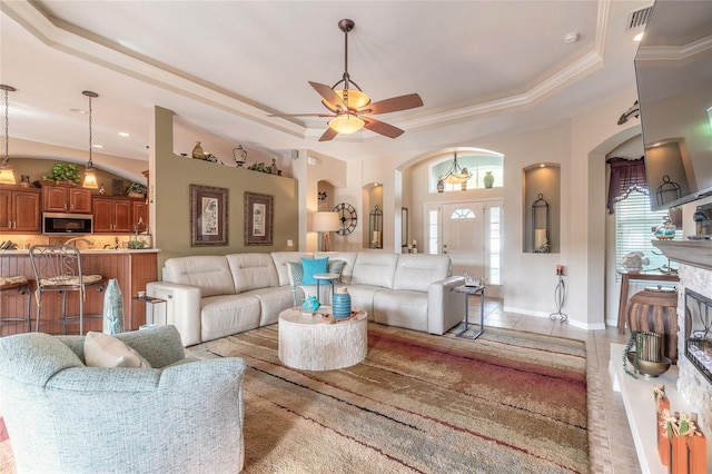 tiled living room with a tray ceiling, ceiling fan, and ornamental molding