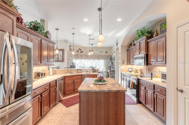 kitchen with tasteful backsplash, stainless steel appliances, ceiling fan, pendant lighting, and a center island