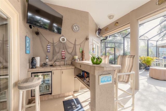 kitchen with tile counters, sink, wine cooler, kitchen peninsula, and white cabinets